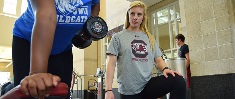 personal trainer working with a student lifting weights