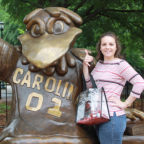 woman with clear bag beside Cocky statue