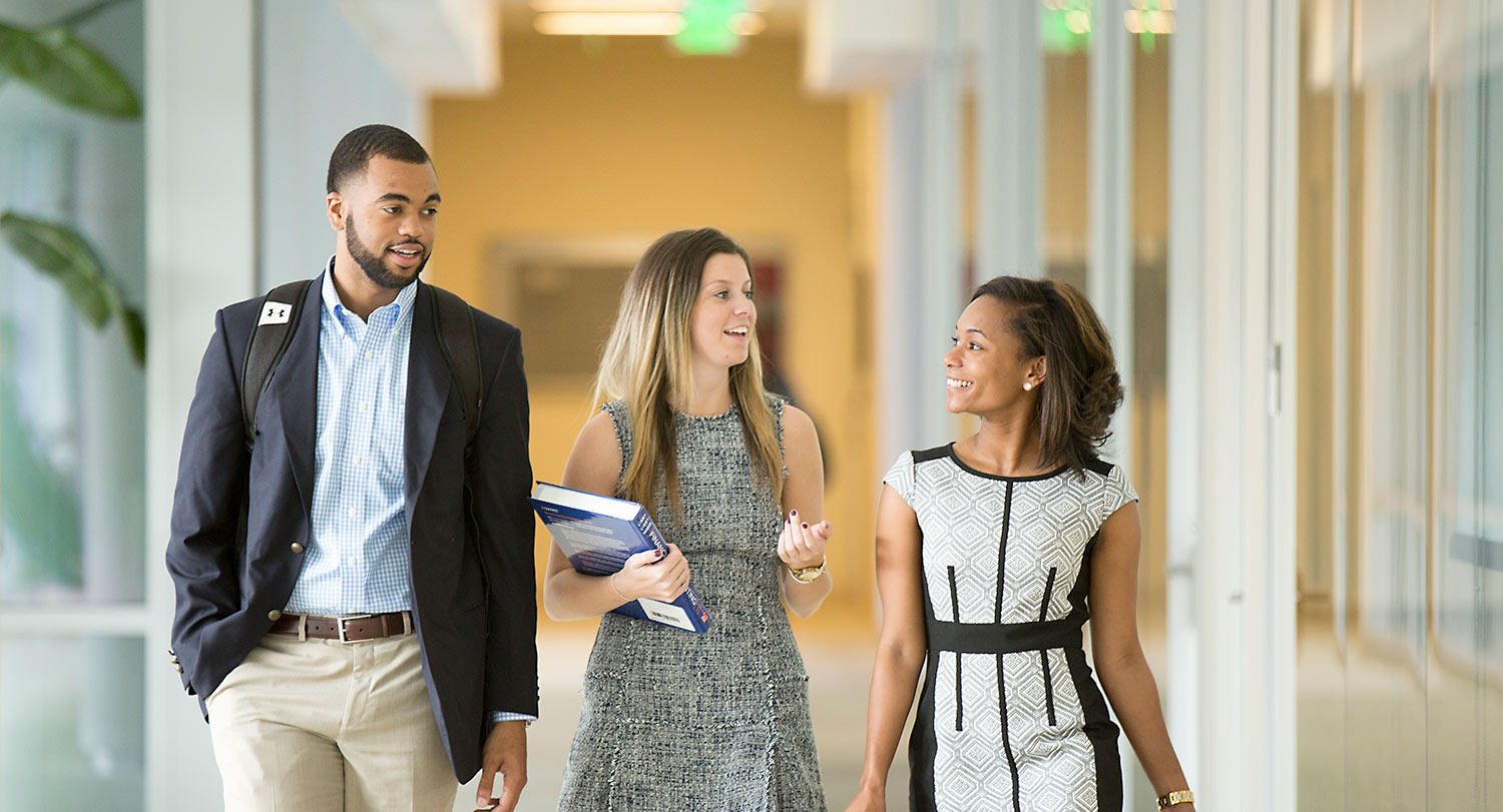 Three professionally dressed people walking down a hall. 