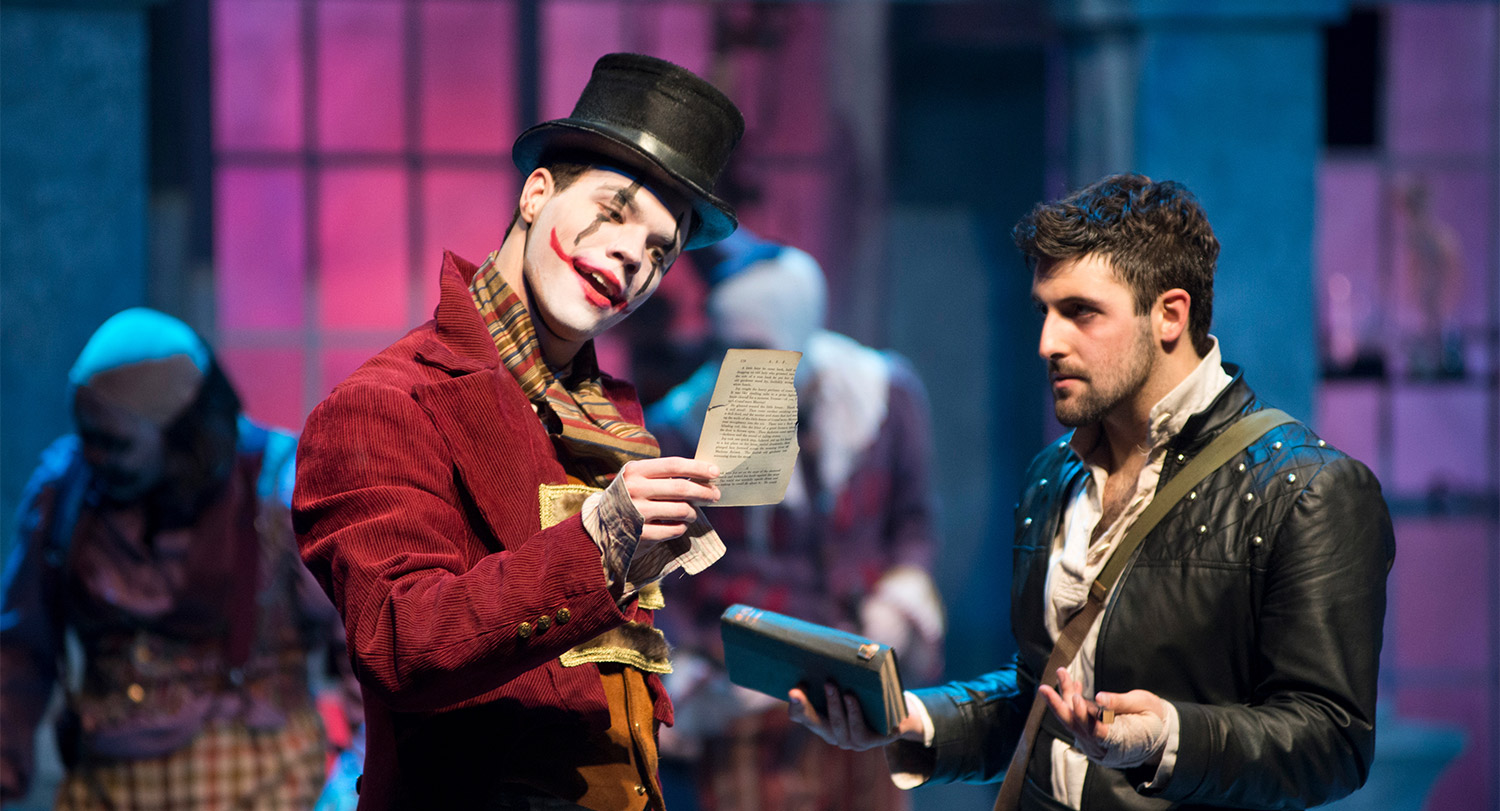 Students in full costume on stage acting in a play.