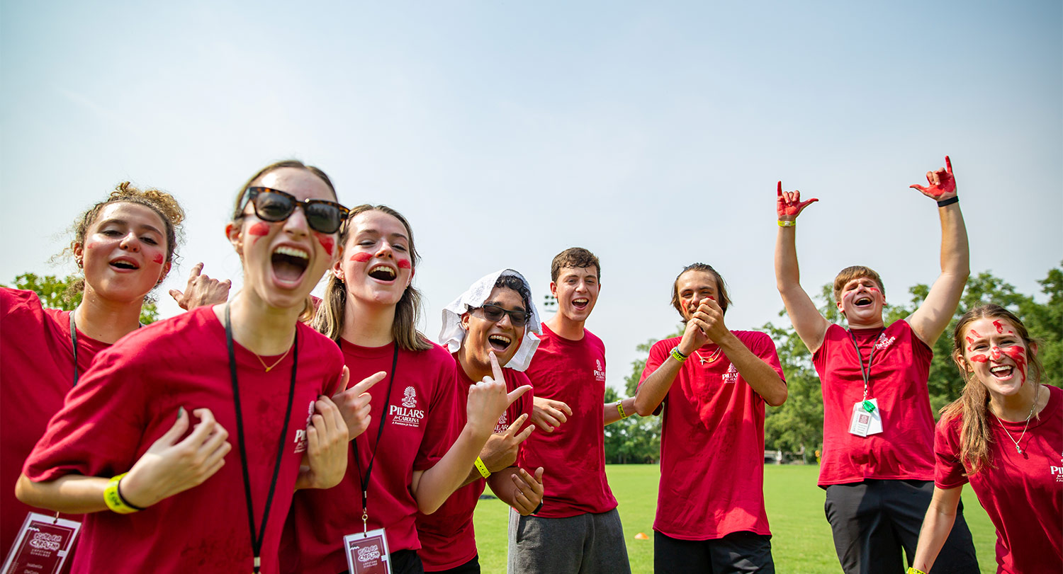 Students in garnet shirts and face paint yell excitedly at the camera. 