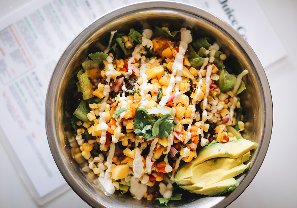 A Southwest bowl with romaine, black beans, mango salsa, avocado, sharp cheddar, sweet corn, cilantro and green onion.