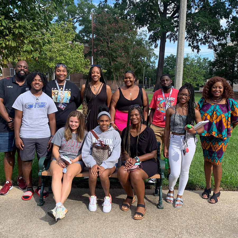 groupof smiling students. ACI coach Preston Thorne stands at let and ODEI Dean Glori Boutte stands at right.