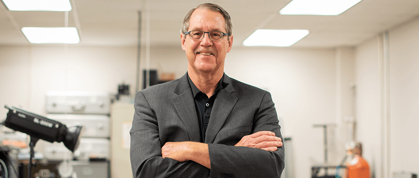 Dr. Sutton stands in lab with arms crossed