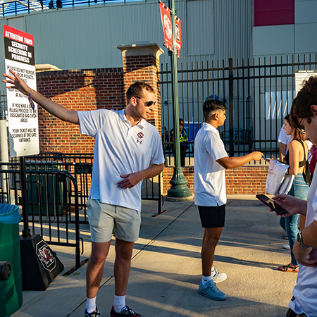 Two students working at a Gamecock football game assist fans with questions.