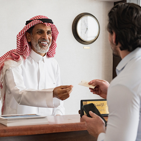 A hotel receptionist hands a guest a room card.