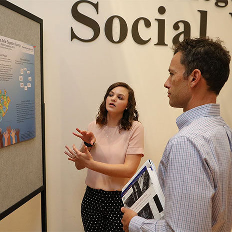 student gestures to her poster