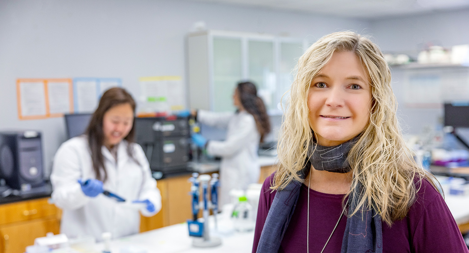 Melissa Moss stands in front of students working in her lab.