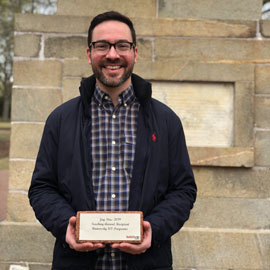 Jay Pou holding horseshoe brick that says his award