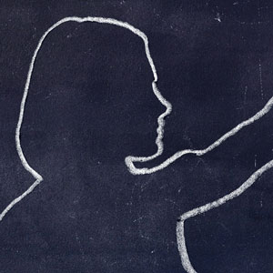 The outline of a teacher in chalk on a blackboard.