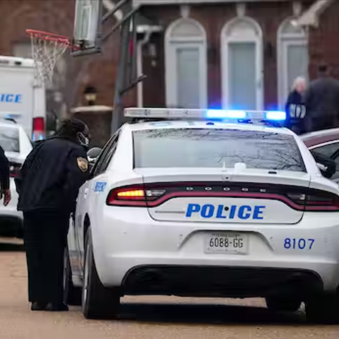 A police officer leans into the window of a police car