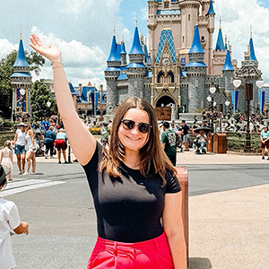 Woman with arm up in front of Walt Disney World castle