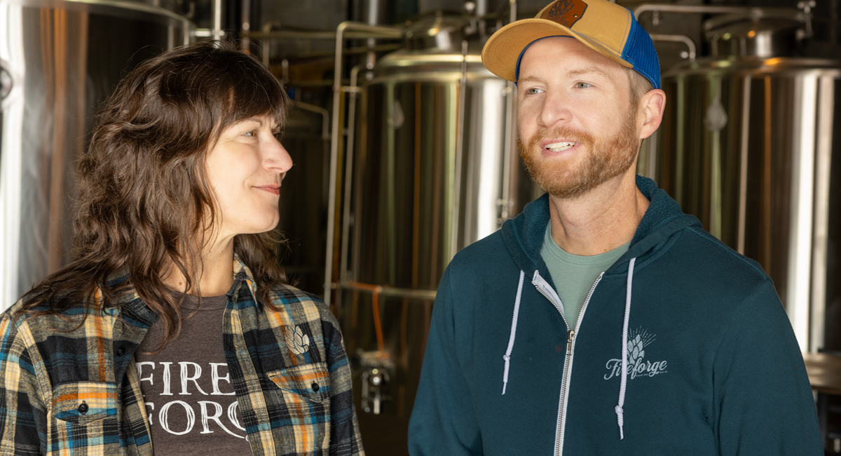 two people stand in front beer vats