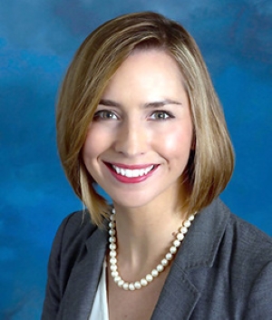 Amanda Fairchild, smiling, wearing a gray blazer over a white top with a pearl necklace.