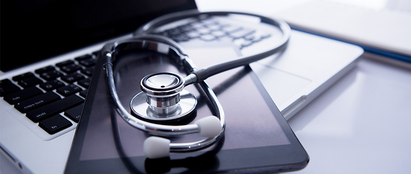 Decorative banner photo of a laptop computer and tablet arranged with a stethoscope.