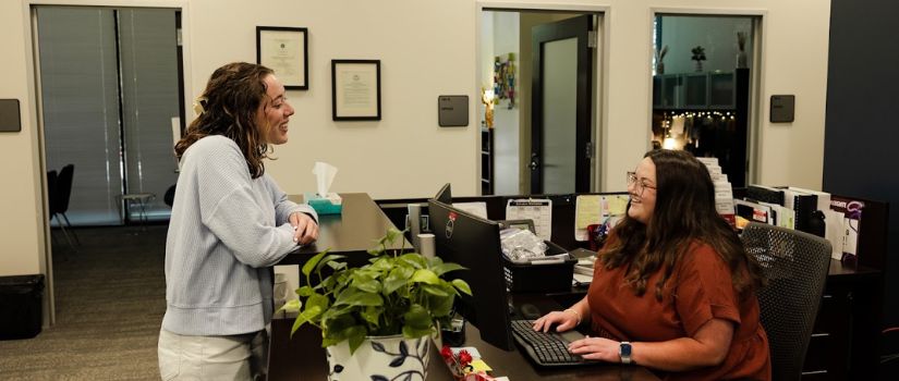 student talking to employee at a desk 