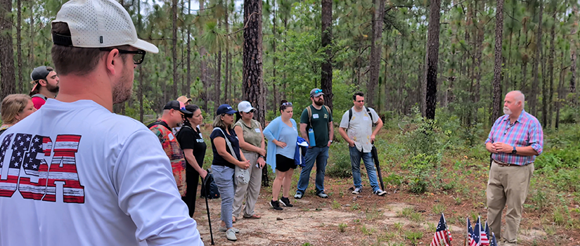 group standing in forest listening to lecture
