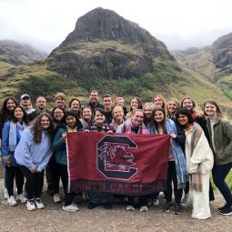 Group of students holding USC flag by mountain peak