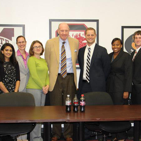 Neville Isdell poses with students and faculty after visiting with a class