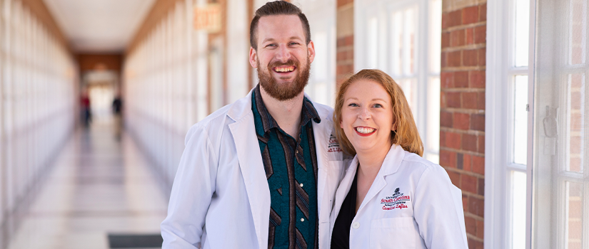 Caroline and Gannett Loftus pose in the halls of the school of medicine in their white coats