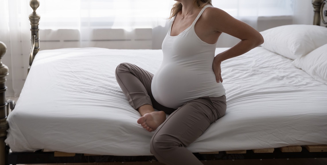 pregnant woman sitting on bed