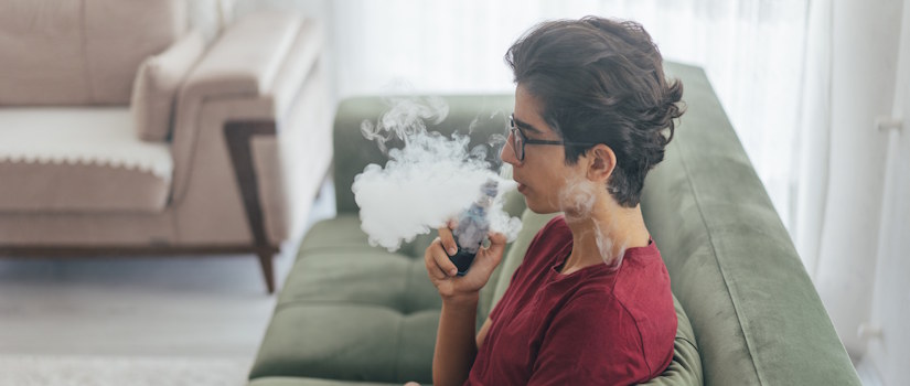 teen vaping on couch