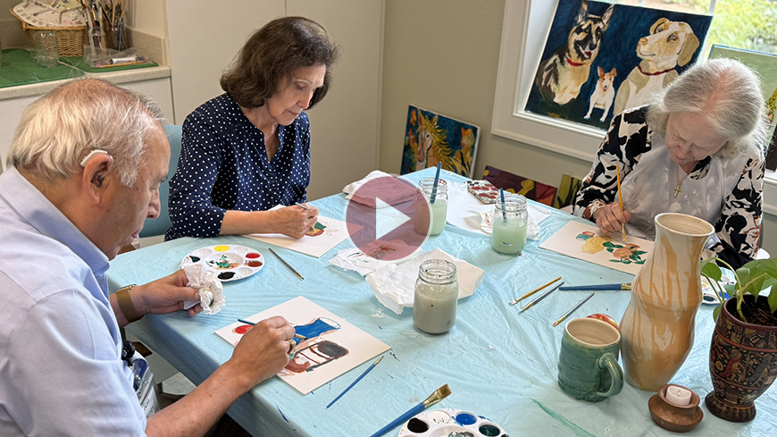 Residents work on paintings at a table.