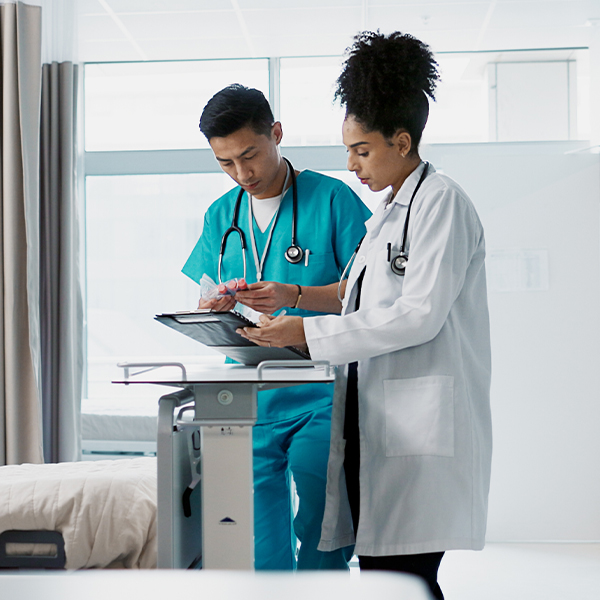 A doctor and nurse review a chart together in a hospital room