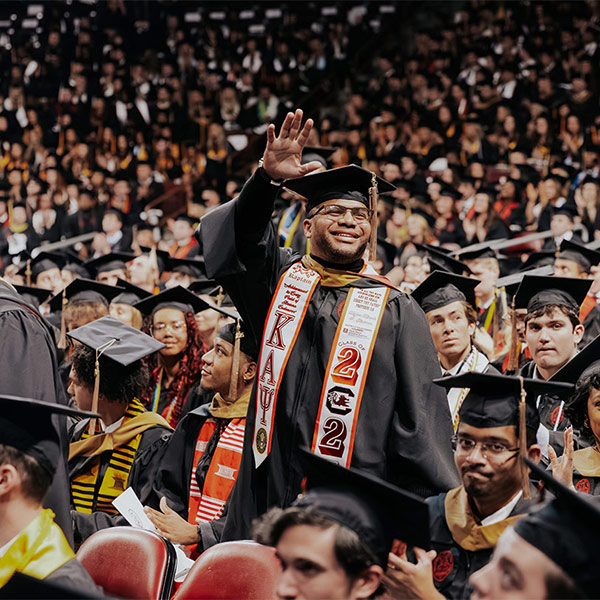 Student stands and waves at commencement cermony