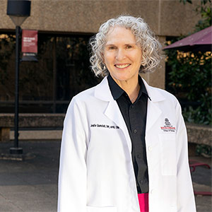 Woman standing outdoors in white lab coat on USC campus