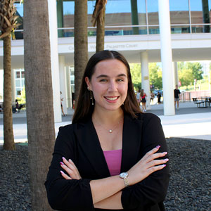 Breanna Price crosses her arms and smiles in front of the business school
