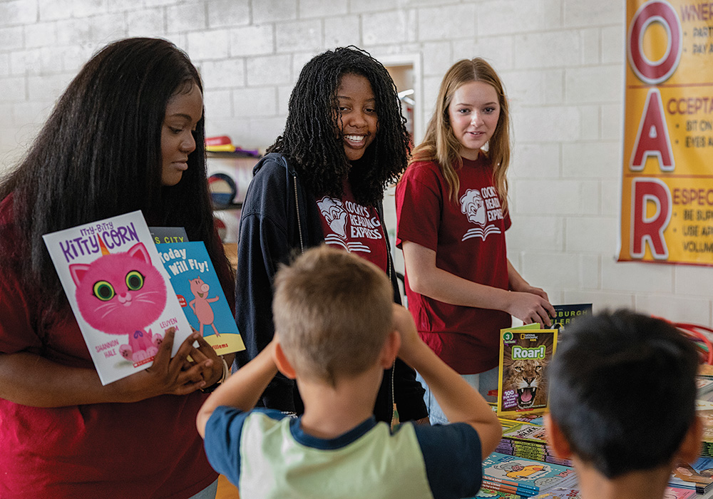 Student volunteers (from left to right) Faith Moody, Briana Vinson and Elena Pueschel hand out free books.