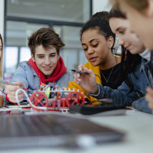 A group of high school students building and programming electric toys and robots at robotics classroom