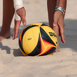 a close up of a person's hands reaching for a volleyball 