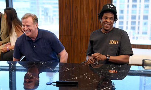 A white adult male in blue polo shirt (left) sits at table with African American adult male in black t-shirt and ballcap